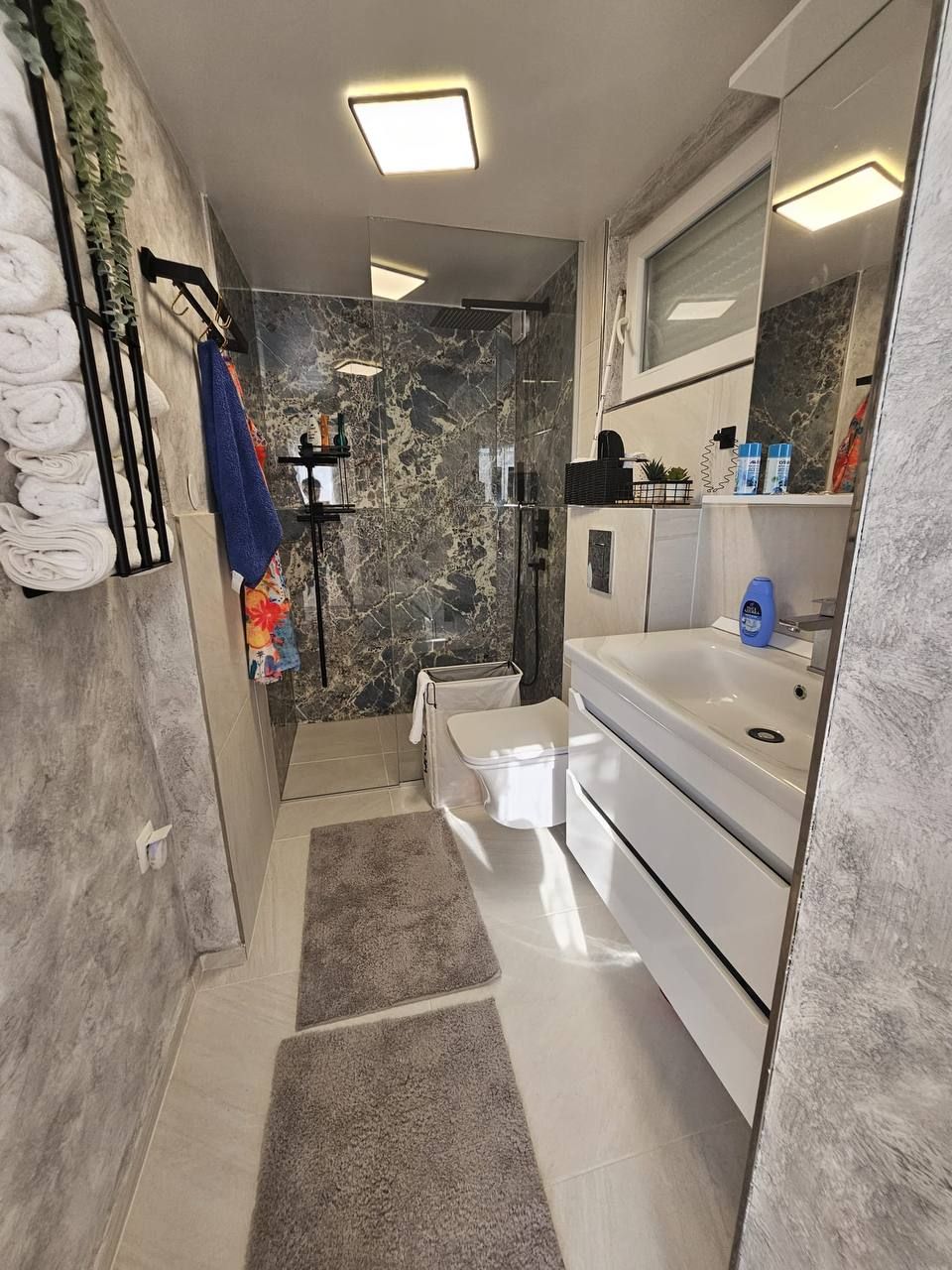 Modernes Bad mit Regendusche und Natursteinwand