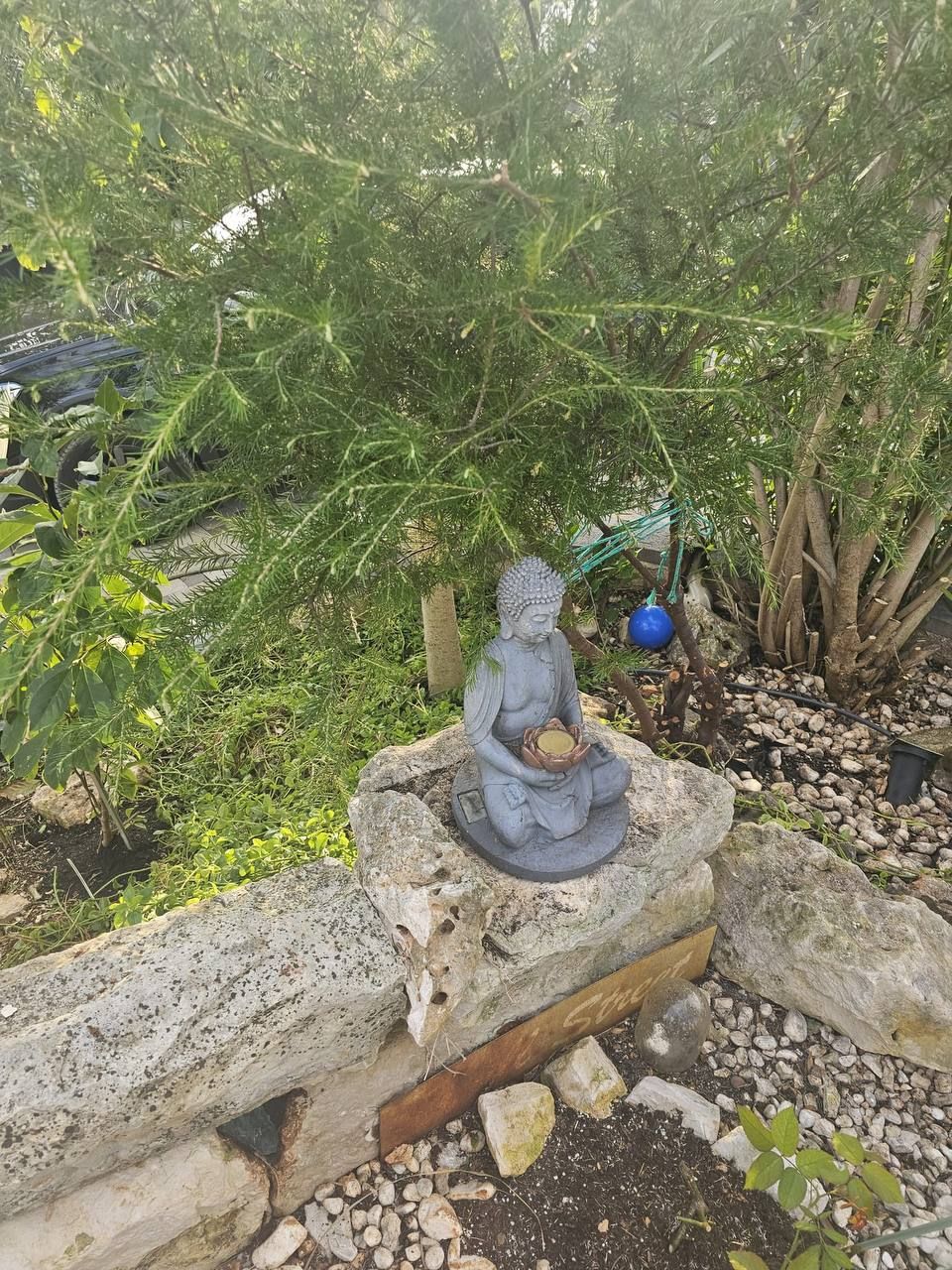 Buddha-Figur zwischen Steinen und Gräsern im Garten