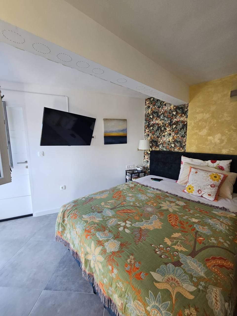 Schlafzimmer mit Smart-TV und floraler Akzentwand