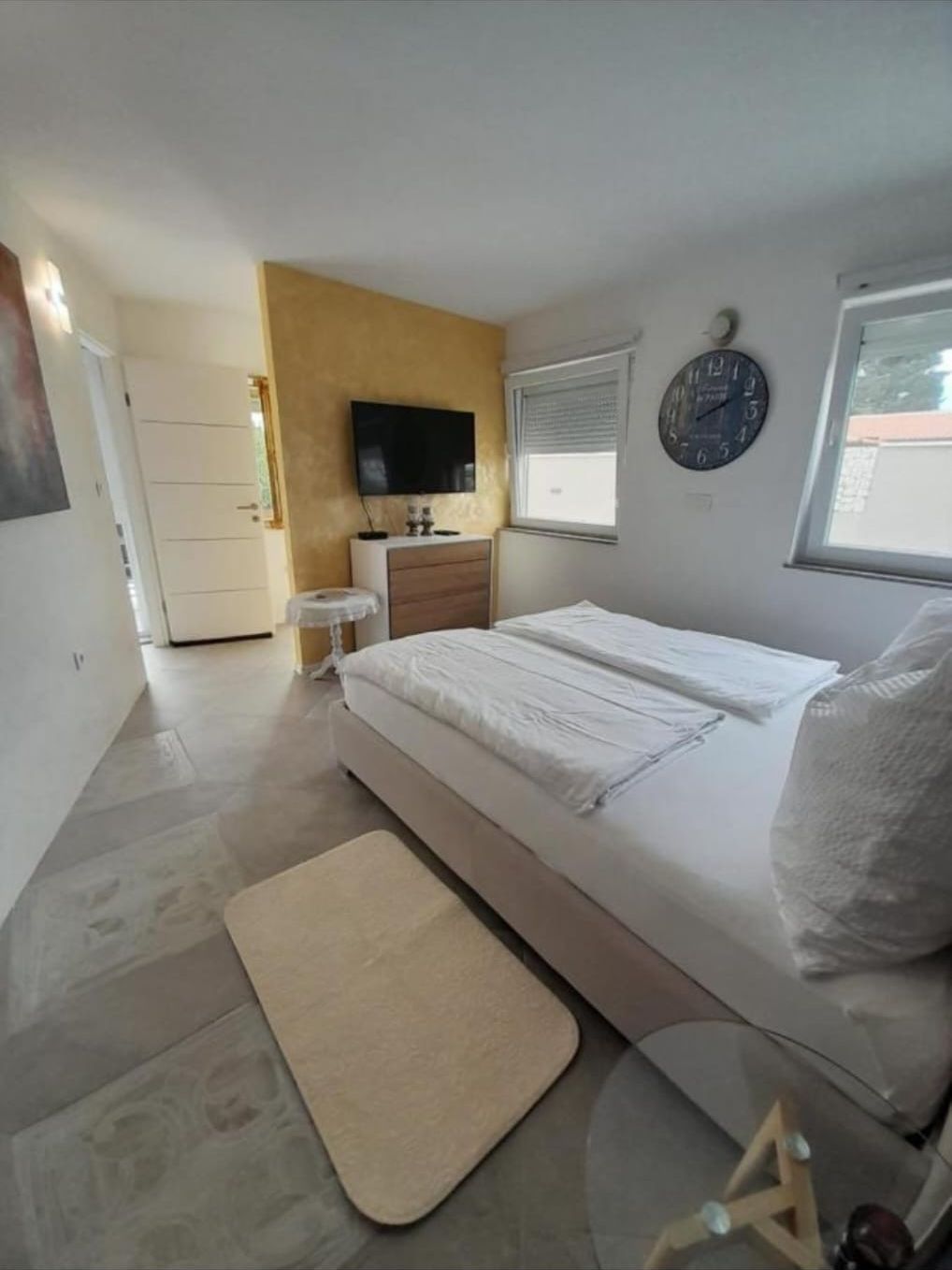 Helles Schlafzimmer mit Doppelbett und Wanduhr