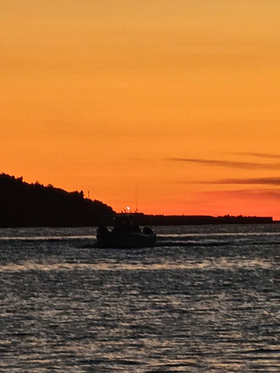 Orangefarbener Sonnenuntergang mit Boot auf dem Meer