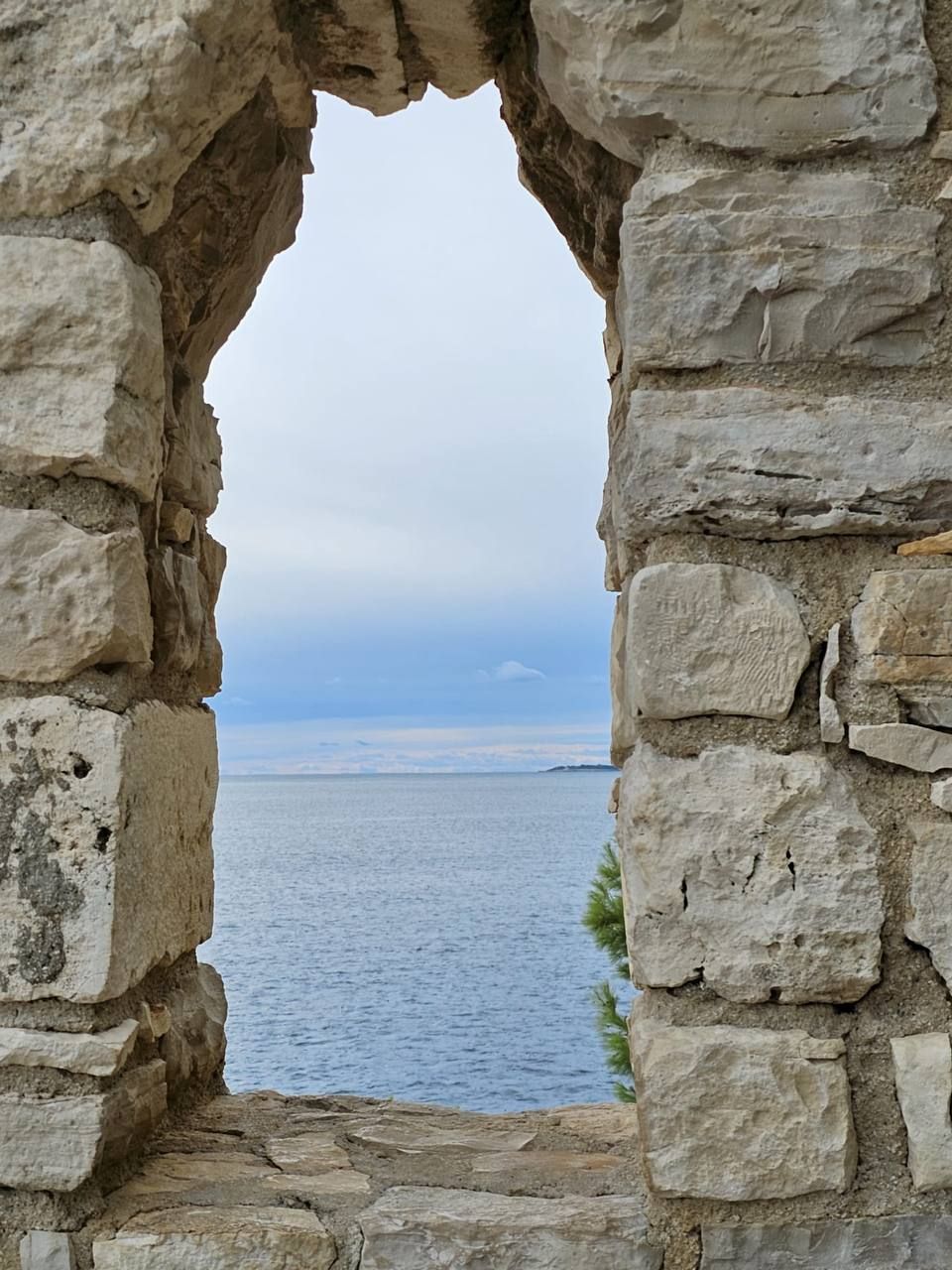 Blick durch ein altes Steinfenster aufs Meer